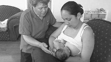 Midwife helping young mum breastfeed baby.