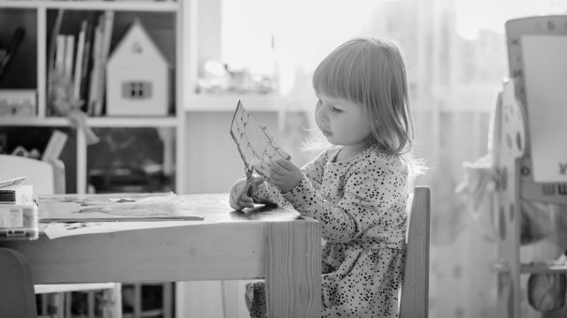 Child seated at table reading.