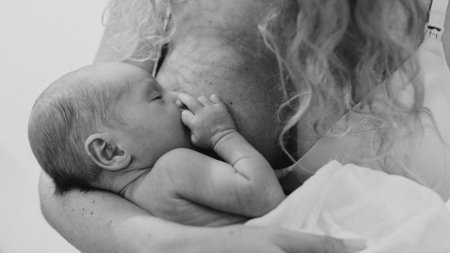 close up image of newborn baby breastfeeding.