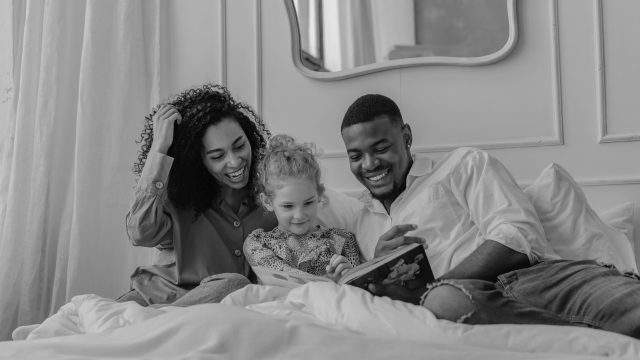 Mother and father reading to daughter before bed.