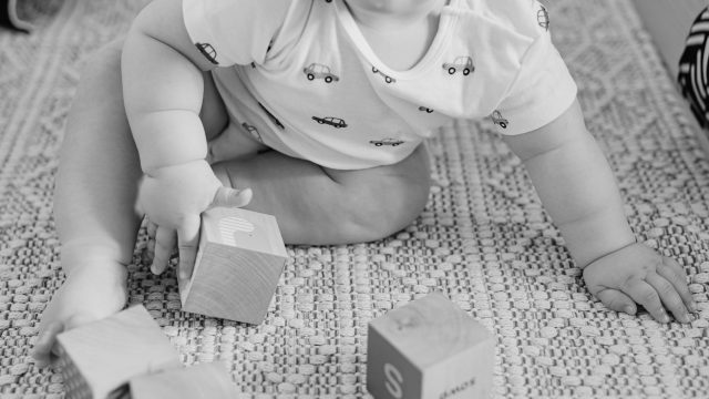 Close up image of baby playing on floor with blocks.
