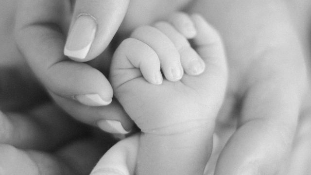 Baby's newborn hand inside of mothers hand.