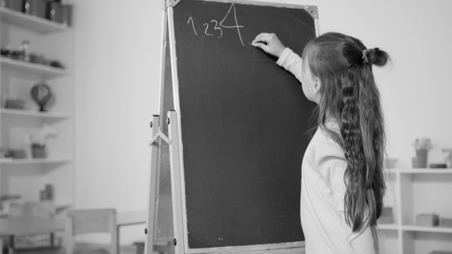 Child doing maths on calkboard.