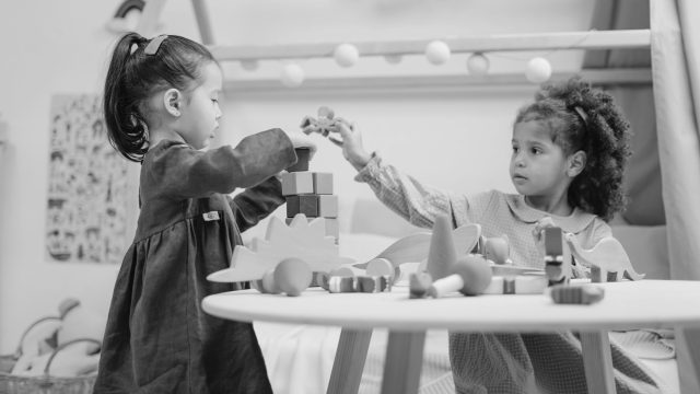 Kids play with blocks together at a table in playroom.