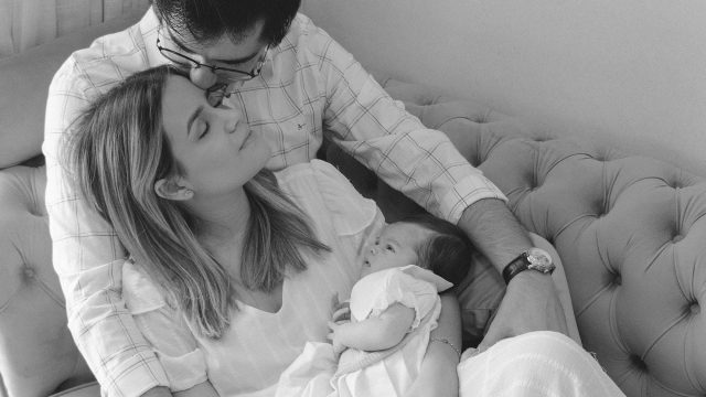 new family pictured together holding baby on couch.