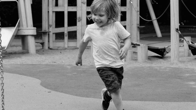 Young boy runs excitedly around playground.