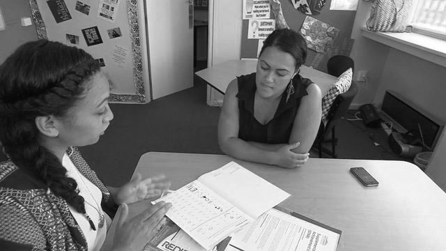 Two women sit at table discussing home school education.